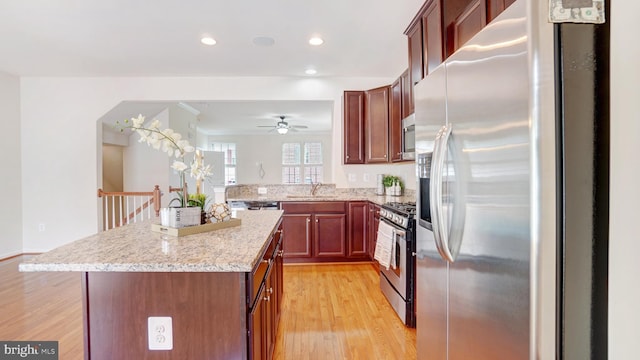 kitchen featuring sink, a center island, light stone counters, light hardwood / wood-style floors, and stainless steel appliances