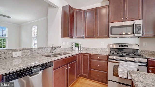 kitchen with sink, ornamental molding, stainless steel appliances, light stone countertops, and light wood-type flooring