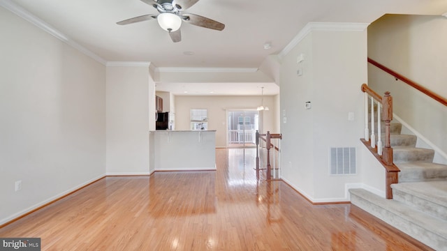 spare room with ornamental molding, ceiling fan with notable chandelier, and light hardwood / wood-style flooring