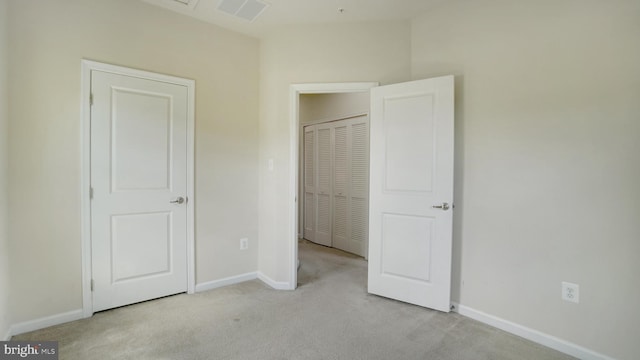 unfurnished bedroom featuring light carpet and a closet