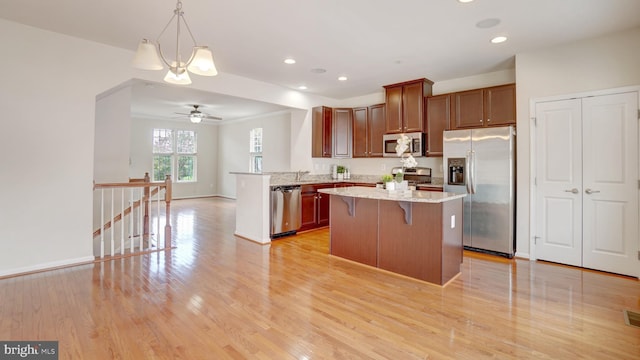 kitchen featuring pendant lighting, a breakfast bar, stainless steel appliances, light stone countertops, and kitchen peninsula