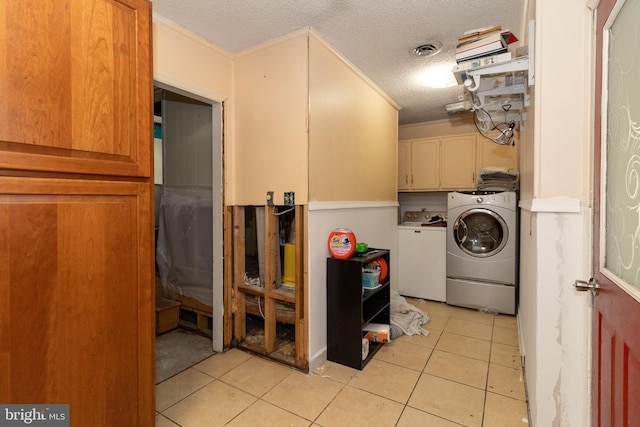 laundry room with light tile patterned floors, washing machine and dryer, cabinets, and a textured ceiling