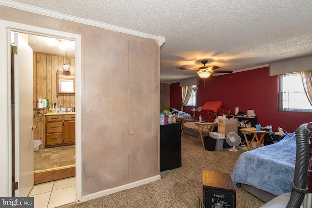 bedroom featuring ornamental molding, light carpet, a textured ceiling, and wood walls