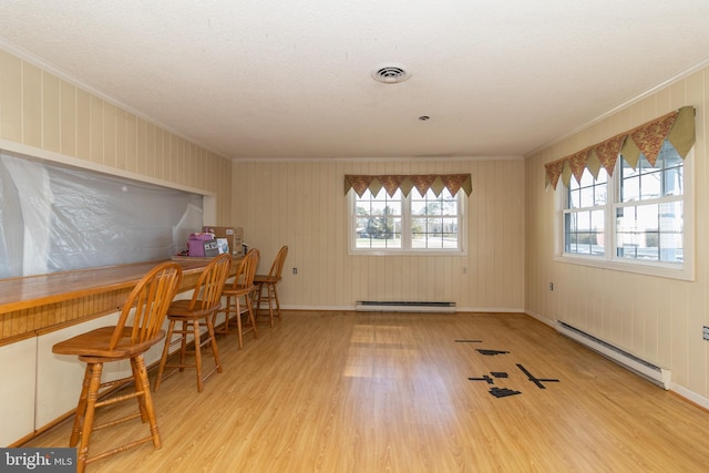 dining room with ornamental molding, light hardwood / wood-style floors, and a baseboard heating unit