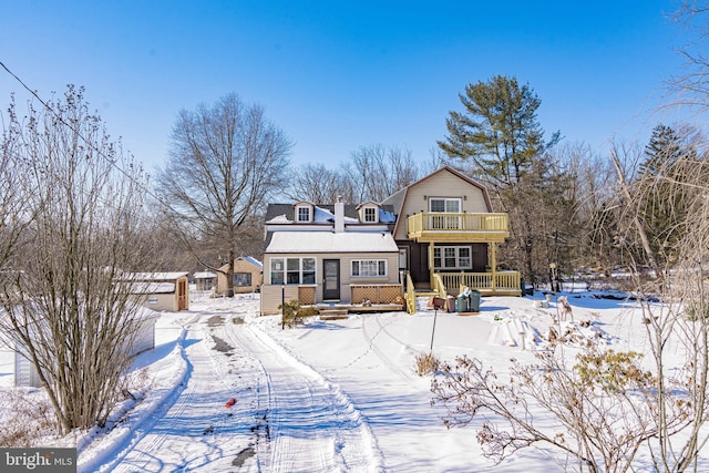 snow covered rear of property with a balcony and covered porch