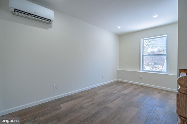 unfurnished room featuring hardwood / wood-style floors and a wall mounted air conditioner