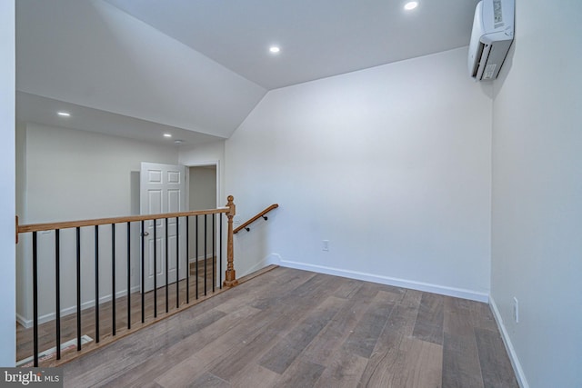 hallway with hardwood / wood-style flooring, lofted ceiling, and a wall mounted air conditioner