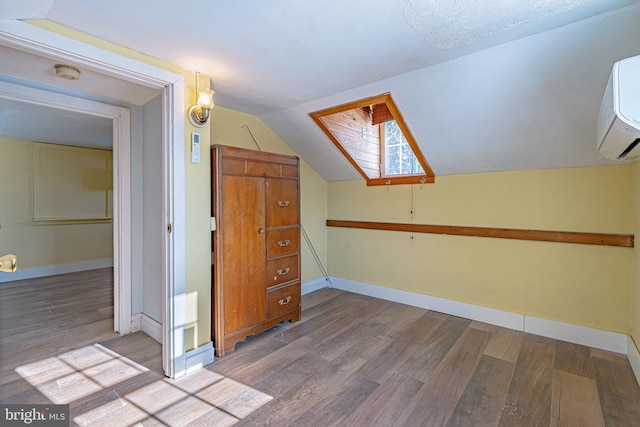 bonus room with wood-type flooring, lofted ceiling with skylight, and a wall mounted air conditioner