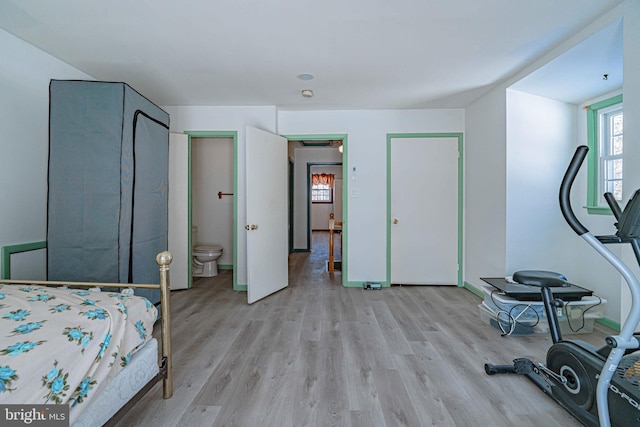 bedroom featuring connected bathroom and light wood-type flooring