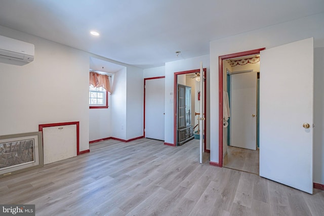 unfurnished room with a wall unit AC and light wood-type flooring