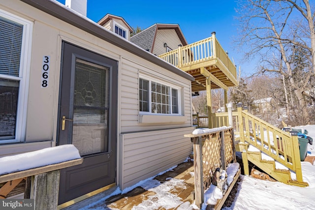 snow covered property entrance featuring a balcony