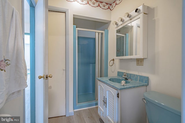 bathroom with wood-type flooring, toilet, a shower with door, and vanity