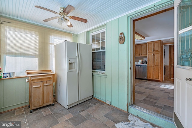 kitchen with ceiling fan, stainless steel dishwasher, wood walls, and white fridge with ice dispenser