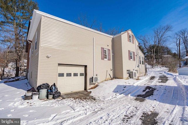 snow covered property featuring a garage and ac unit