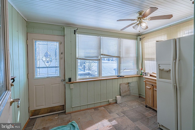 interior space with crown molding, ceiling fan, and wood walls