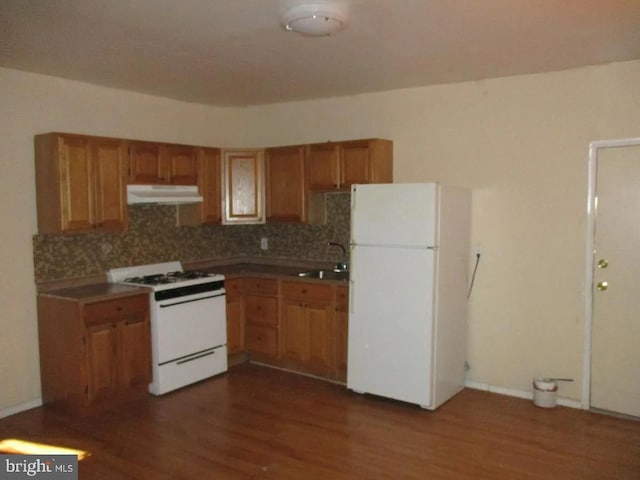 kitchen featuring white appliances, dark hardwood / wood-style floors, sink, and backsplash