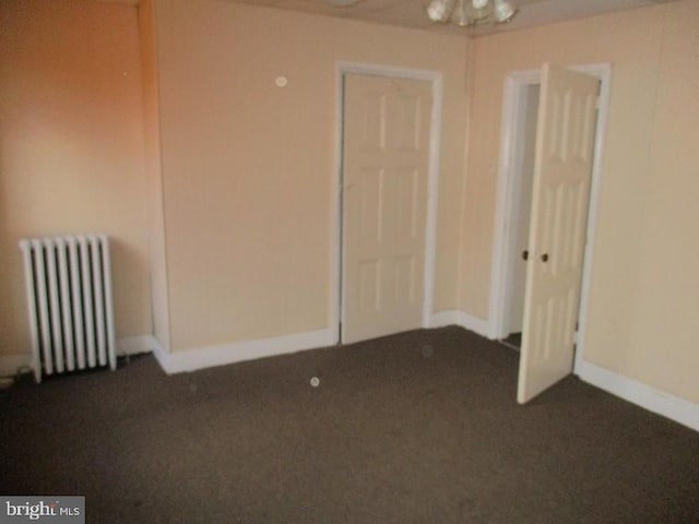 carpeted empty room featuring radiator heating unit