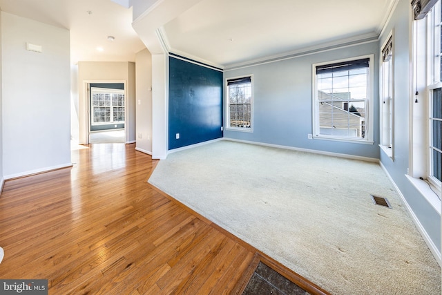 empty room with a healthy amount of sunlight, visible vents, and crown molding