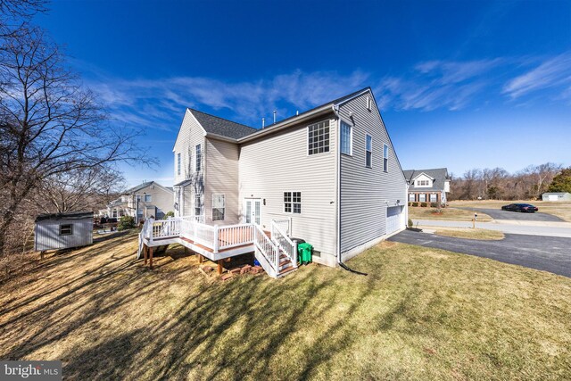 view of side of home with a lawn, a storage shed, a garage, driveway, and an outdoor structure