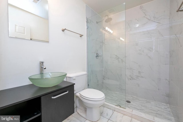 bathroom with toilet, vanity, and a tile shower