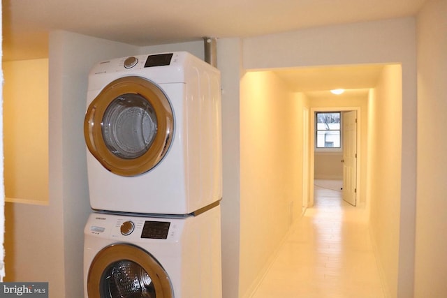 clothes washing area with stacked washing maching and dryer