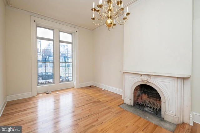 unfurnished living room with light wood-type flooring, a notable chandelier, and ornamental molding