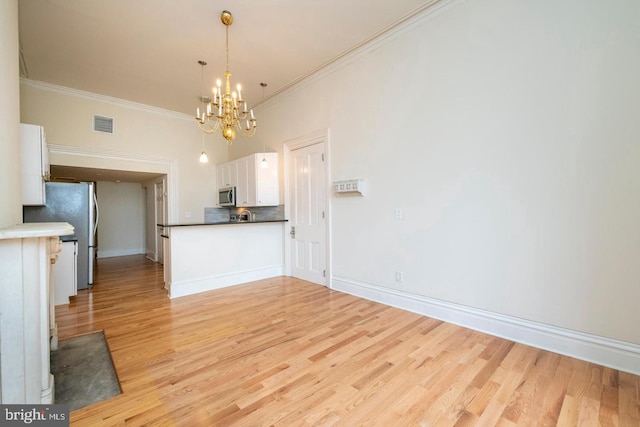 kitchen with crown molding, decorative light fixtures, white cabinetry, light hardwood / wood-style floors, and stainless steel appliances