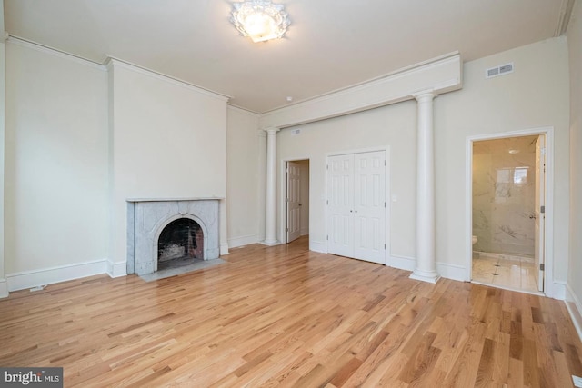 unfurnished living room with decorative columns, ornamental molding, and light hardwood / wood-style floors