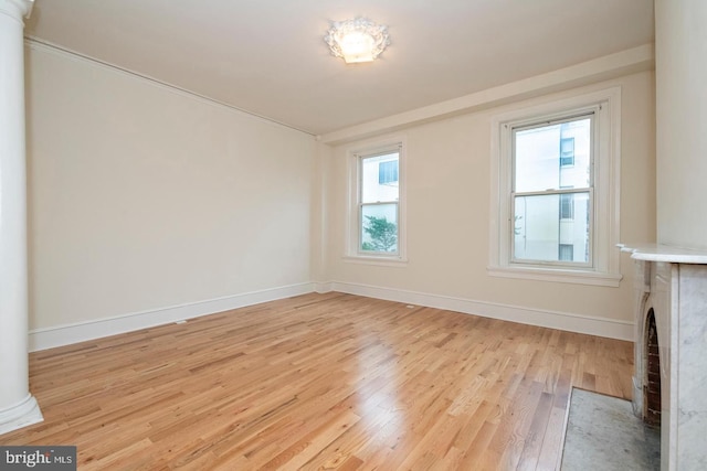 unfurnished living room featuring decorative columns and light hardwood / wood-style flooring