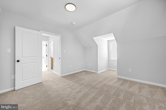 additional living space featuring light colored carpet and lofted ceiling