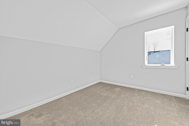 bonus room with light carpet and vaulted ceiling