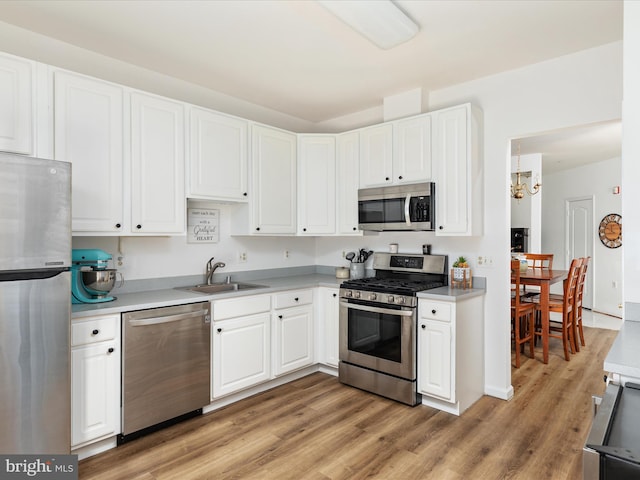 kitchen featuring white cabinetry, sink, light hardwood / wood-style floors, stainless steel appliances, and an inviting chandelier