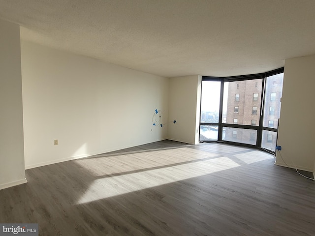 unfurnished room with floor to ceiling windows, hardwood / wood-style floors, and a textured ceiling