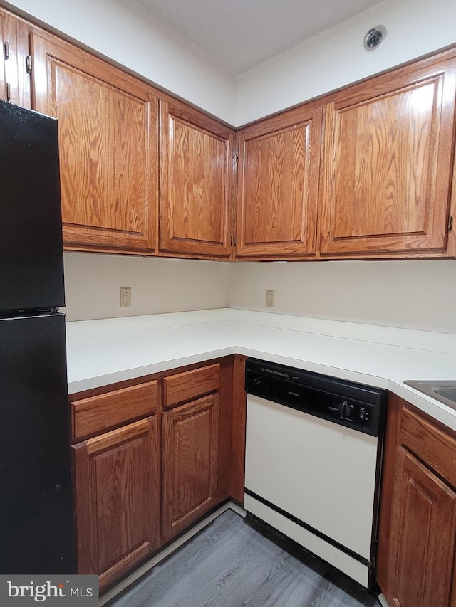 kitchen featuring white dishwasher, dark wood-type flooring, and black fridge