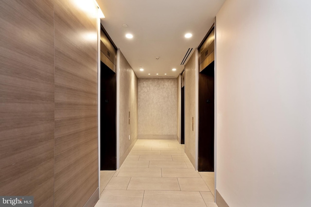 hall featuring light tile patterned floors and wooden walls