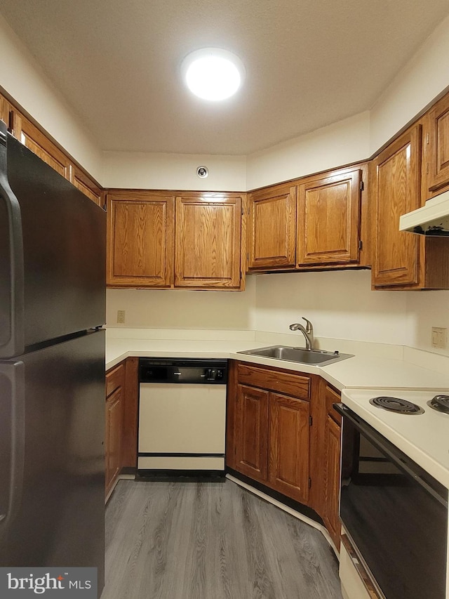 kitchen featuring range with electric cooktop, dishwasher, sink, black fridge, and dark wood-type flooring