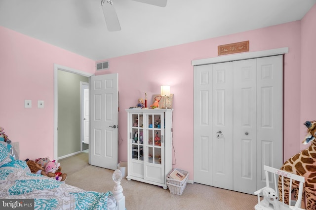 bedroom with ceiling fan, light colored carpet, and a closet