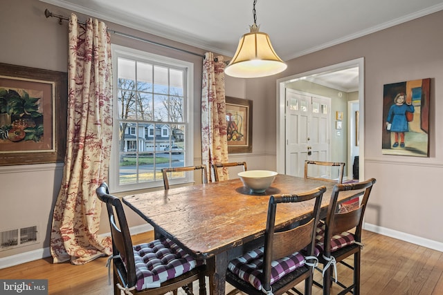 dining space featuring ornamental molding and light hardwood / wood-style floors