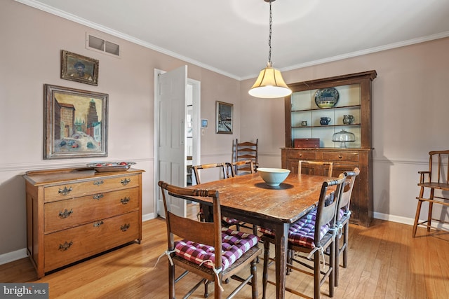 dining space with crown molding and light hardwood / wood-style flooring