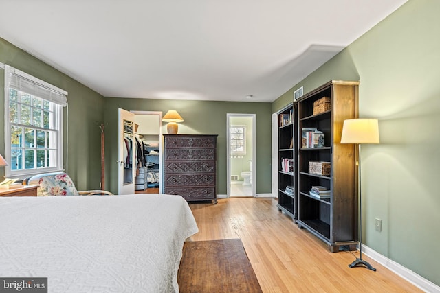 bedroom with hardwood / wood-style flooring, ensuite bath, a closet, and a spacious closet