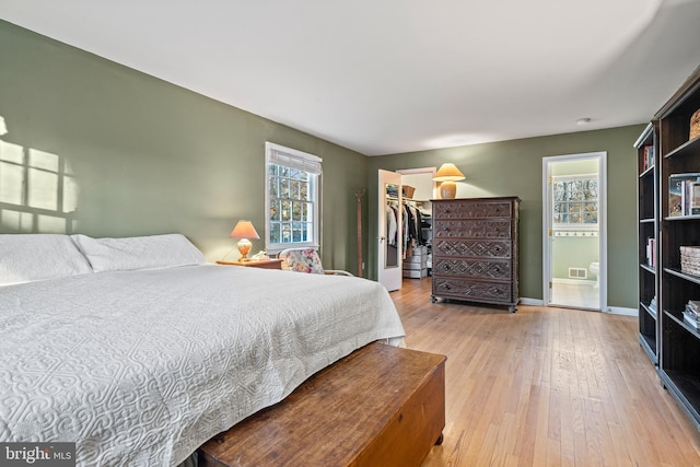 bedroom with a walk in closet, light hardwood / wood-style floors, and a closet