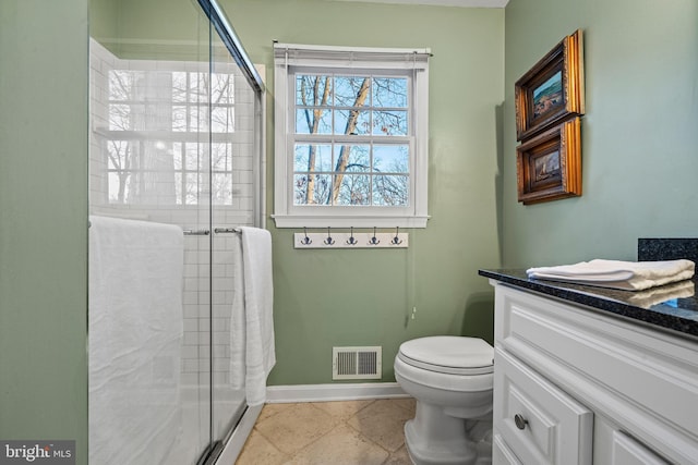 bathroom featuring vanity, toilet, and a shower with door