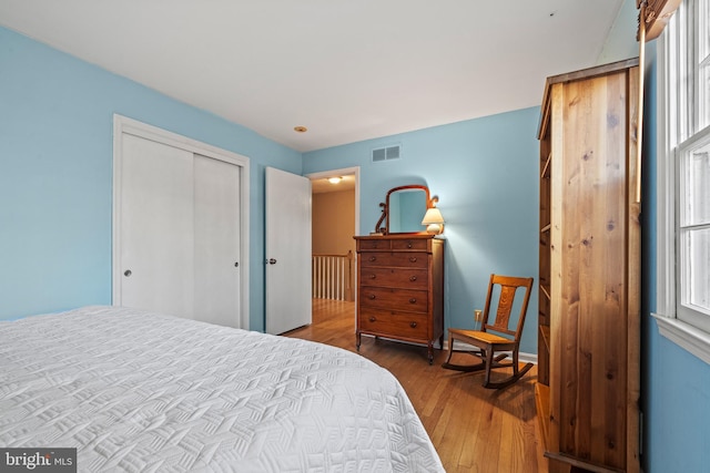 bedroom with hardwood / wood-style flooring, a closet, and multiple windows