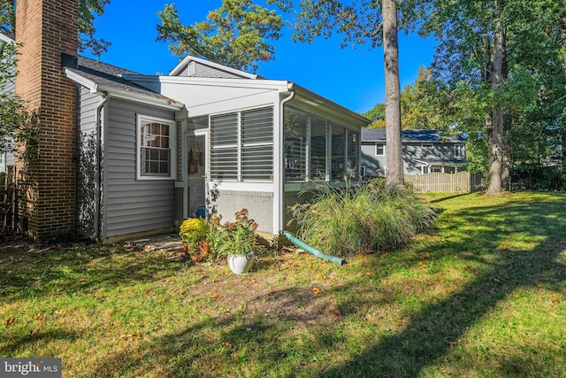 view of side of home with a sunroom and a yard