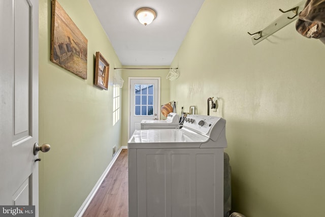 laundry area with light hardwood / wood-style floors and washing machine and clothes dryer