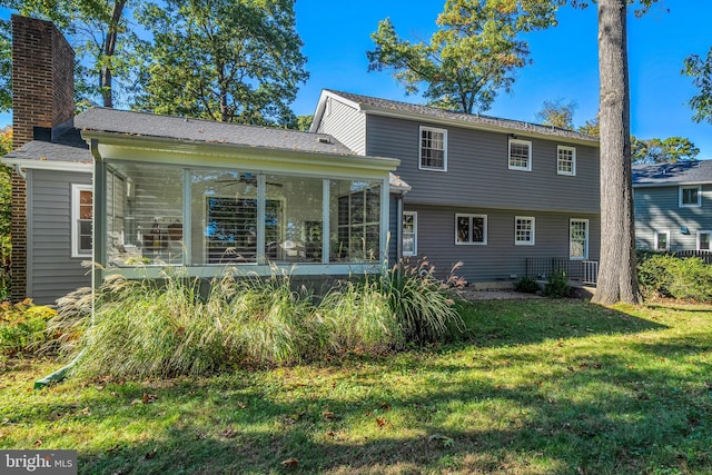 rear view of property featuring a lawn, a sunroom, and ceiling fan