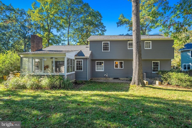 rear view of house with a sunroom and a lawn