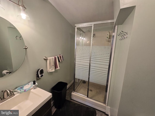 bathroom featuring a shower with door and vanity