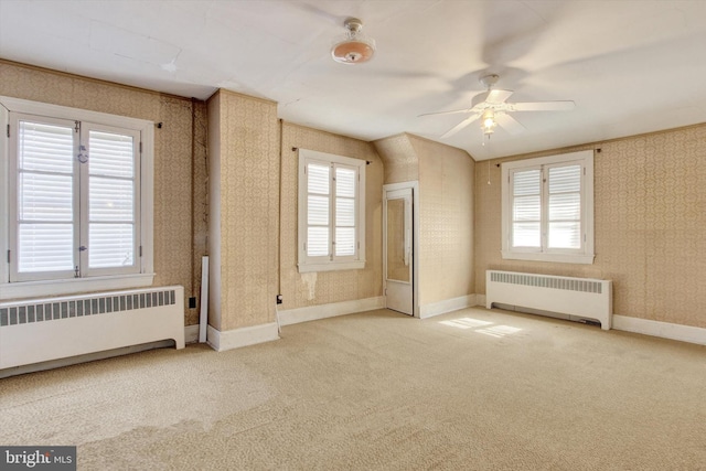 empty room featuring a wealth of natural light, radiator heating unit, and wallpapered walls