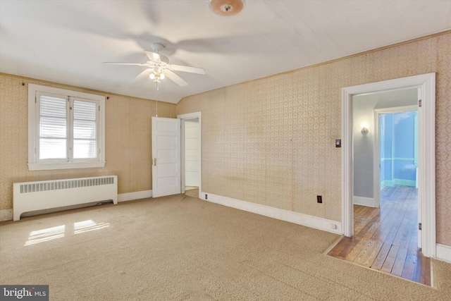 interior space featuring wallpapered walls, radiator, and baseboards